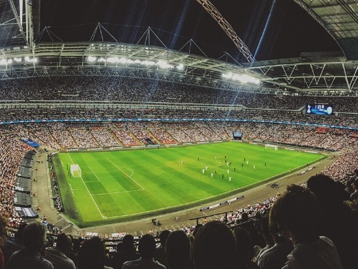 Das Foto zeigt ein großes Fußballstadion und weist damit darauf hin, wie viele Spieler mit ganz oder teilweise ausländischer Herkunft in der deutschen Fußball-Nationalmannschaft spielen.